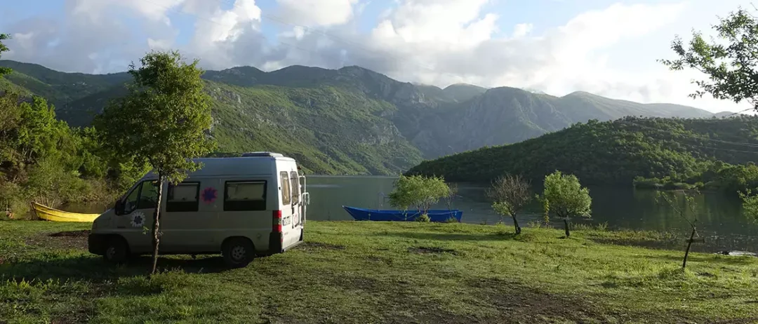 agora camping, agora farmhouse camping, Campingplatz in Albanien, Wohnmobil im vordergrundauf der Grünfläche zusehen, dahinter ein großer See und Berge